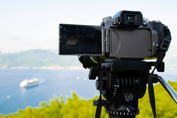 Camera on a tripod filming cruise ship sailing across the Adriatic Sea in Bay of Kotor Montenegro.