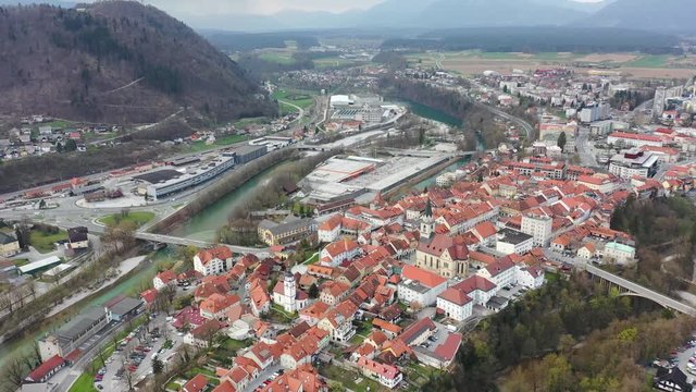 Forward flying drone aerial over downtown area of Kranj, Slovenia. New industrial part if visible next to it, with hills and mountains visible in distance