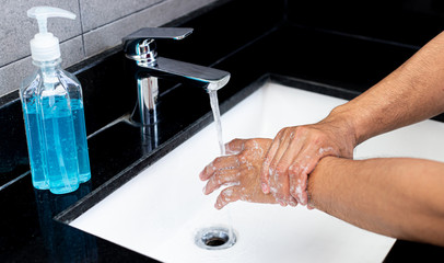 Man is washing his hands in a sink sanitizing the colona virus for sanitation and reducing the spread of COVID-19 spreading throughout the world, Hygiene ,Sanitation concept.