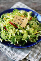 Selective focus. A note with the words cbd food in a plate of salad. Cannabis food concept.