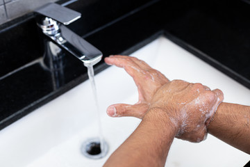 Obraz premium Man is washing his hands in a sink sanitizing the colona virus for sanitation and reducing the spread of COVID-19 spreading throughout the world, Hygiene ,Sanitation concept.