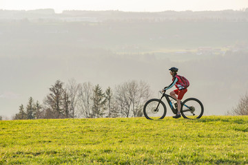 pretty senior woman riding her electric mountain bike in early springtime in the Allgau mountains...