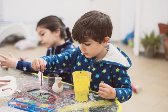 Two brothers in the courtyard of their house paint ceramic figures and make crafts
