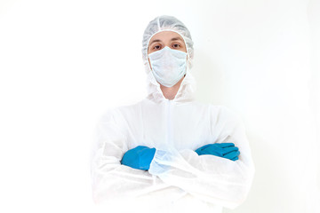 A man in a protective suit and face mask looks at the camera with his arms folded. Isolated on a white background.