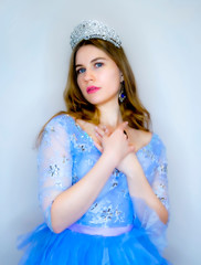 Beautiful young woman in gorgeous blue long dress like Cinderella with perfect make-up and hair style