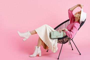 Full-length studio fashion portrait of young elegant happy smiling woman wearing trendy spring outfit: pink blouse, white hat, pleated skirt, ankle boots, holding stylish faux leather bag - obrazy, fototapety, plakaty