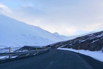 Dark road on the background of snowy mountains and sky