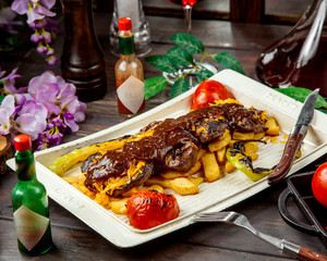 lamb steak pieces garnished with sauce served with french fries and smoked vegetables