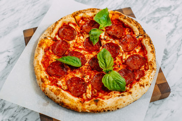 Italian pizza with mozzarella cheese and basil on a marble table
