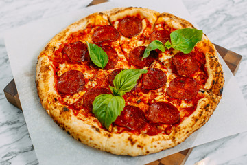 Italian pizza with mozzarella cheese and basil on a marble table