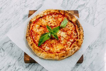 Italian pizza with mozzarella cheese and basil on a marble table