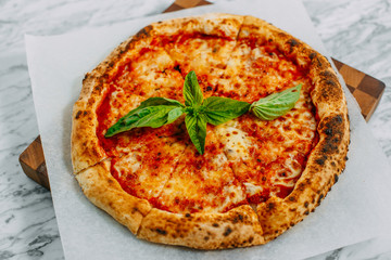 Italian pizza with mozzarella cheese and basil on a marble table