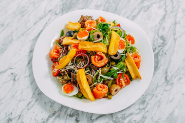 salad with salmon, caviar, eggs and vegetables on a marble table