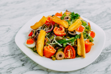 salad with salmon, caviar, eggs and vegetables on a marble table
