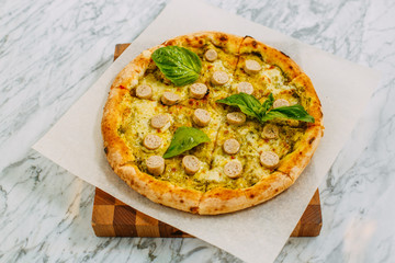 Italian pizza with mozzarella cheese and basil on a marble table