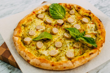 Italian pizza with mozzarella cheese and basil on a marble table
