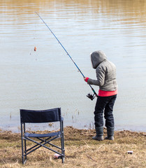 The girl catches fish in the lake for fishing rod.