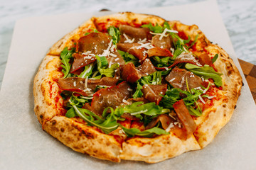 Italian pizza with mozzarella cheese and basil on a marble table