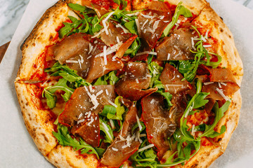 Italian pizza with mozzarella cheese and basil on a marble table