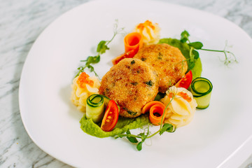 fish cakes with caviar and vegetables on a marble table