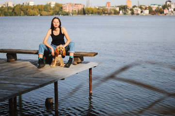 Girl with her dog, English Cocker Spaniel, sitting on the bench near the lake