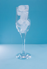 A glass of ice on a blue background.Tableware for alcohol.A glass for champagne and wine.Chilled drinks.