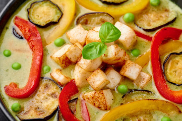 Vegetarian Thai Green Curry with tofu in black bowl. Veg Green Thai Curry is thailand cuisine dish with green chillies paste, basil, spices and vegetables. Close up. Thai Food