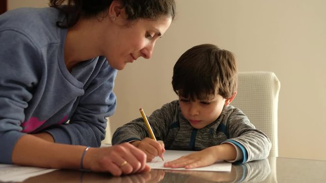 Mother helps little son to do homework at home