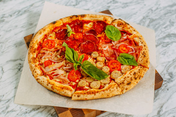 Italian pizza with mozzarella cheese and basil on a marble table