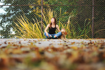 Girl with her dog, English Cocker Spaniel, sitting on the bench near the lake 