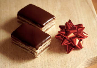 Homemade chocolate cake. Two pieces of tasty Hungarian cake on the wooden kitchen board decorated with red gift bow