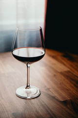 Red wine glass on a wooden table at home