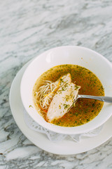 homemade noodle soup with chicken on a marble table