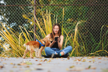 Girl with her dog, English Cocker Spaniel, sitting on the bench near the lake 