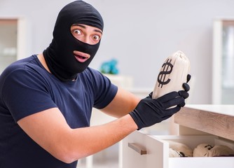 Robber wearing balaclava stealing valuable things