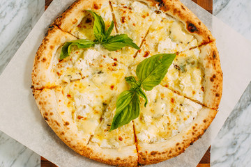 Italian pizza with mozzarella cheese and basil on a marble table