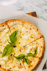 Italian pizza with mozzarella cheese and basil on a marble table