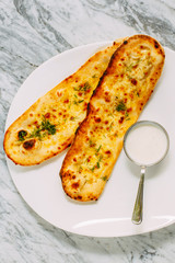 garlic bread with cheese and herbs, with sauce on a marble table