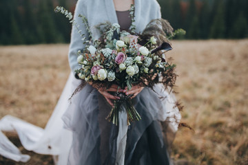 Bridal bouquet. The bride's bouquet. Girl in dress standing on a hillside and is holding a bouquet...