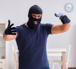 Robber wearing balaclava stealing valuable things