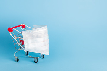 Shopping cart with protective medical mask against coronavirus. Safe and online shopping on...