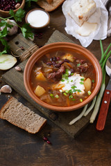 The concept of healthy and diet food. Russian or Ukrainian cuisine. Soup with meat and beans or Borsch served with sour cream on a rustic wooden table. Copy space.