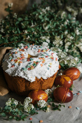 Easter cake and colored eggs on the background of blooming flowers