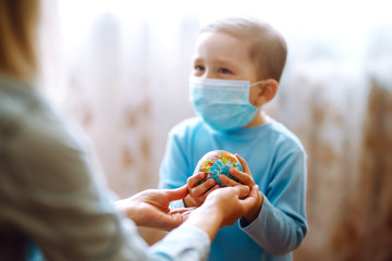 Child in protective sterile medical mask with mother holding a world globe. Save planet. The...