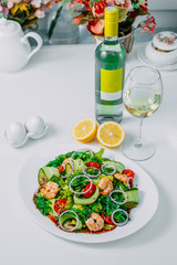 fresh vegetable salad with shrimp, with lemon and wine on a white background