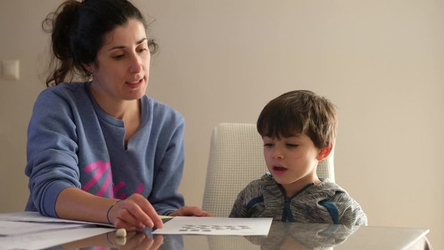 Mother helps little son to do homework at home