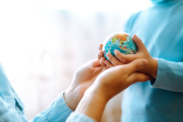Child in protective sterile medical mask with mother holding a world globe. Save planet. The concept of preventing the spread of the epidemic coronavirus.