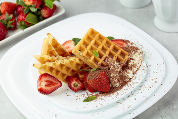 Belgian waffles with strawberries and cream, mint and chocolate chips.