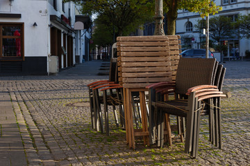 Fototapeta na wymiar Selected focus at stack of outdoor chairs of pub, cafe and restaurant shutdown during quarantine from contagion of COVID-19 on walking street in old town.