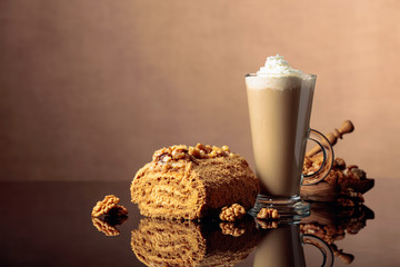 Walnut cake and coffee latte with cream on a reflective background.